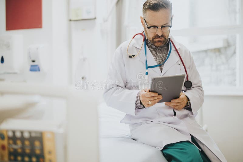 Lectura seria del doctor de una tableta fotografía de archivo libre de regalías Lectura seria del doctor de una tableta fotografía de archivo libre de regalías