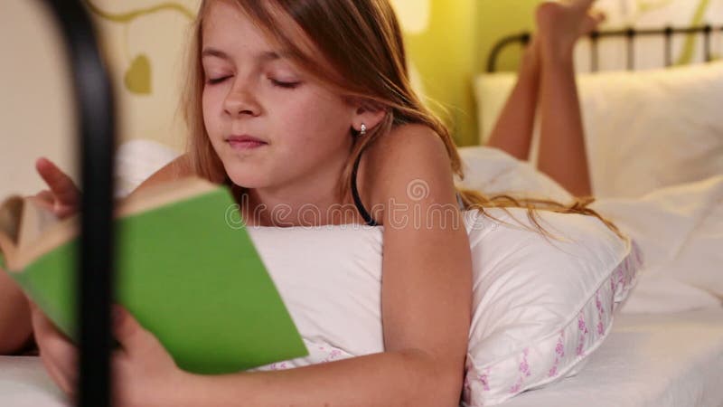 Lecture de jeune fille dans le lit appréciant un bon livre clips vidéos