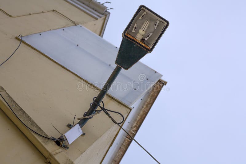 LED fixade på till en krökninglampstolpe framme av en byggnad Lampstolpen klämmas fast på den rosa väggen med trådarna roped runt royaltyfri foto LED fixade på till en krökninglampstolpe framme av en byggnad Lampstolpen klämmas fast på den rosa väggen med trådarna roped runt royaltyfri foto
