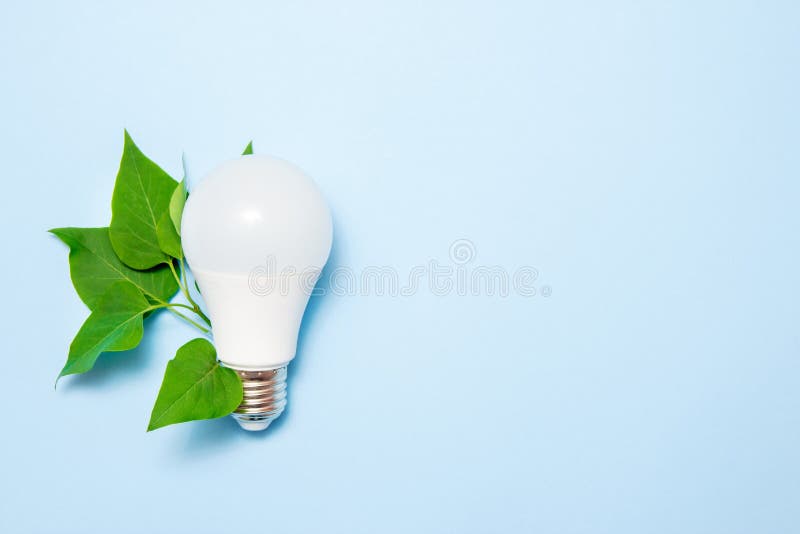 Led Lamp with Leaves on a Blue Background. Green Energy Efficiency