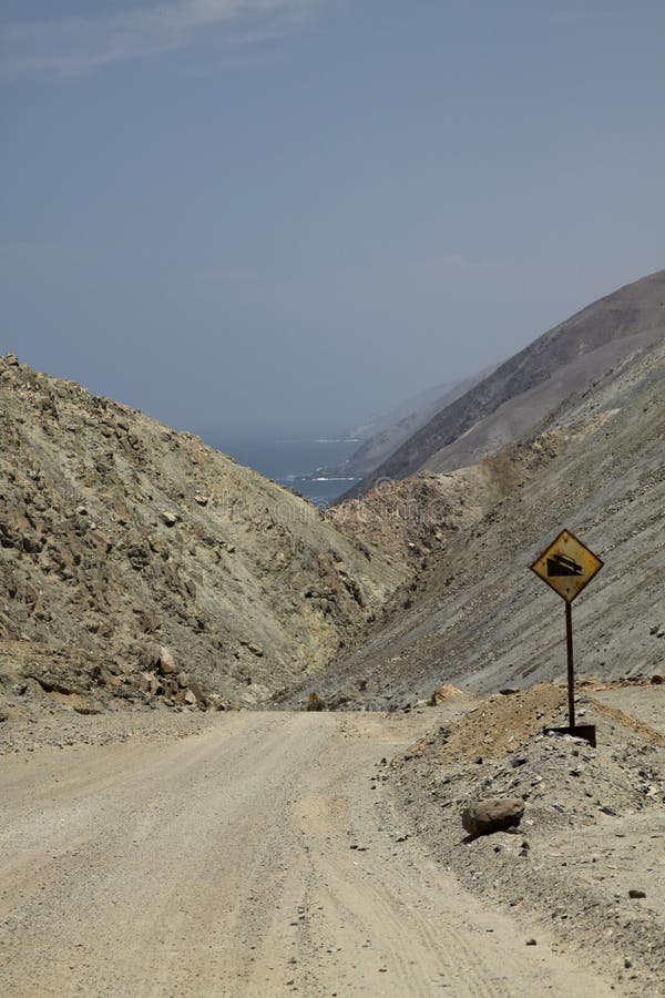 Leda för grusväg som är sluttande till och med stenigt kargt landskap till Stillahavskusten i den Atacama öknen, Chile fotografering för bildbyråer Leda för grusväg som är sluttande till och med stenigt kargt landskap till Stillahavskusten i den Atacama öknen, Chile fotografering för bildbyråer
