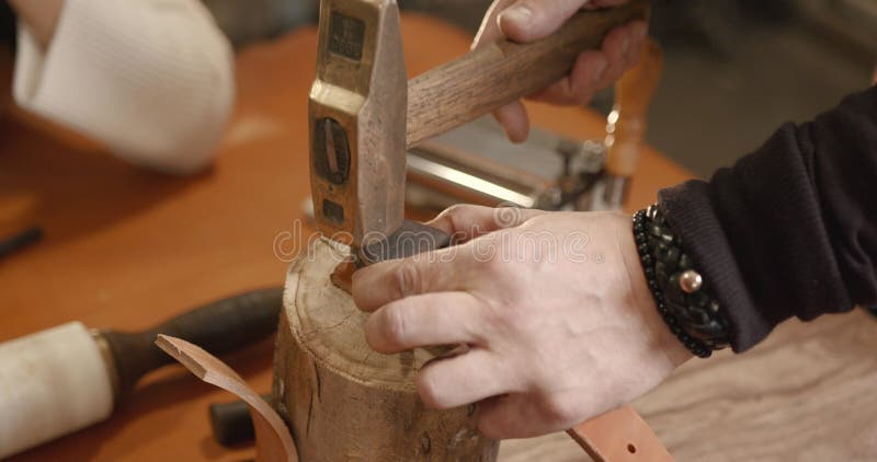 Lederhandwerker, der in einer Werkstatt mit einem Gürtel arbeitet