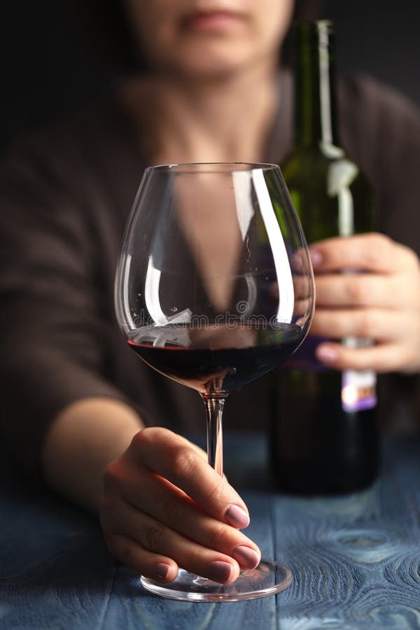 Ledsen och slösad alkoholiserad kvinna som hemma sitter dricka rött vin royaltyfri bild Ledsen och slösad alkoholiserad kvinna som hemma sitter dricka rött vin royaltyfri bild