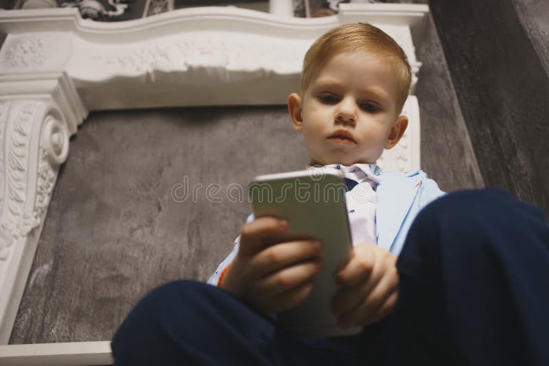 Ledsen pojke som ser mobiltelefonen med handen på huvudet royaltyfri fotografi Ledsen pojke som ser mobiltelefonen med handen på huvudet royaltyfri fotografi