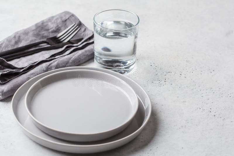 Empty plate and glass of water, white background, copy space. Medical fasting concept. Empty plate and glass of water, white background, copy space. Medical fasting concept