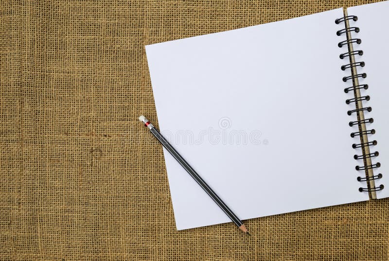 Leeg wit schetsboek en zwart potlood met ruimte op de achtergrond van de jutestof royalty-vrije stock afbeeldingen Leeg wit schetsboek en zwart potlood met ruimte op de achtergrond van de jutestof royalty-vrije stock afbeeldingen