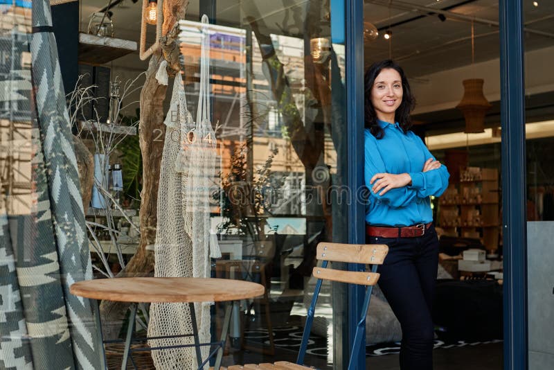 Portrait of a smiling young Asian female entrepreneur standing with her arms crossed at the front door of her trendy shop. Portrait of a smiling young Asian female entrepreneur standing with her arms crossed at the front door of her trendy shop