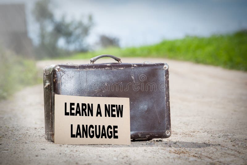 Leer een nieuwe taal Oude reizende koffer bij de landweg