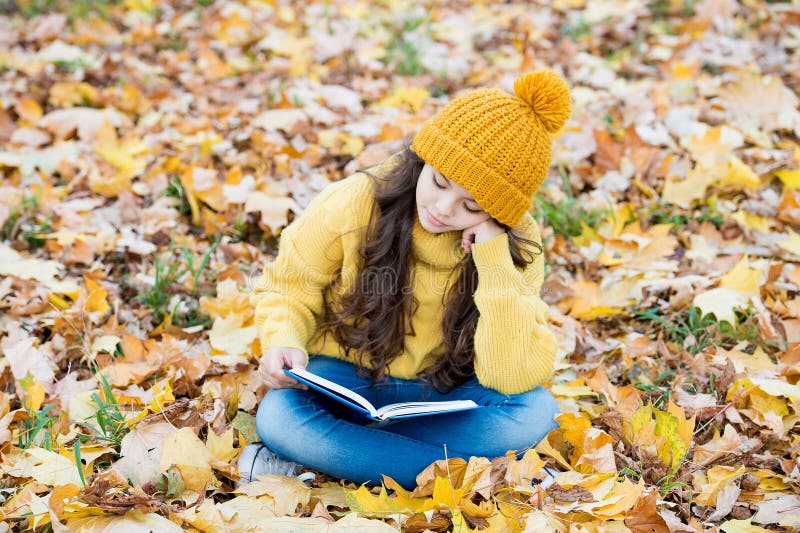 Leer realmente importa. un niño pequeño lee un libro sentado en las hojas del otoño. biblioteca escolar. conocimiento e informació foto de archivo