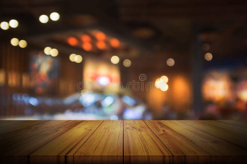 Leere Holztischspitze mit unscharfem hellem BAC des Restaurants oder des Cafés