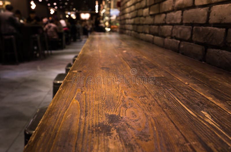Leere hölzerne Tischplatte der Bar mit Unschärfe des Caférestaurants in der Dunkelheit