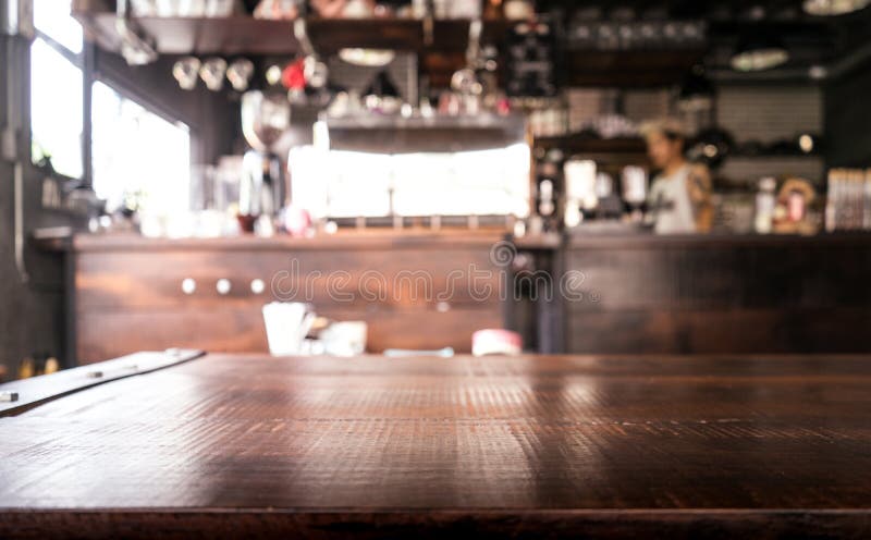 Leere hölzerne Tischplatte mit Unschärfe der abstrakten Kaffeestube oder des Cafés
