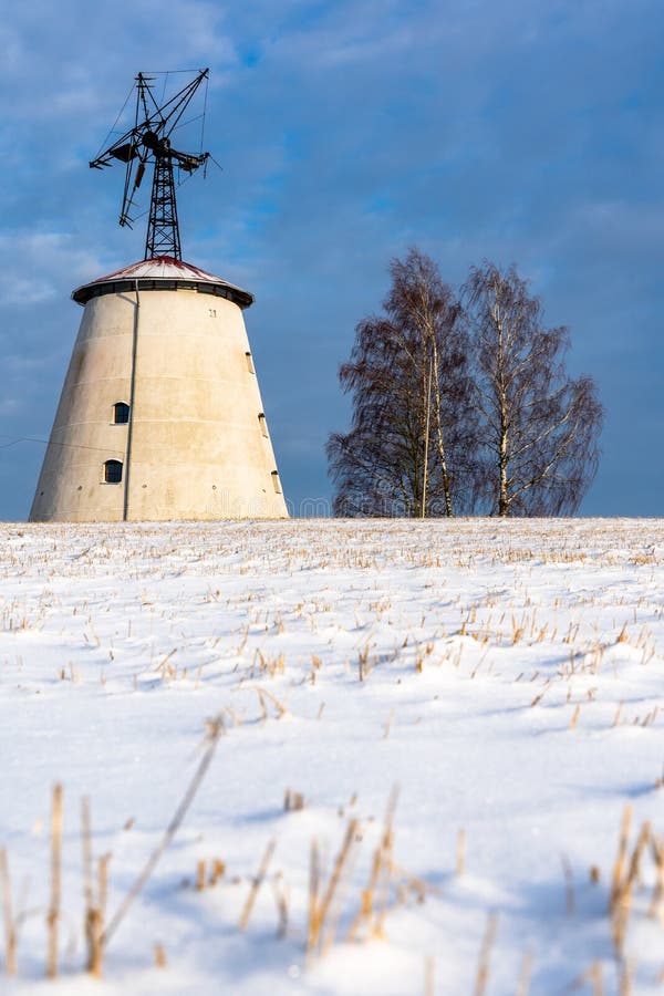 Leere Landschafts-Landschaft in Sunny Winter Day mit dem Schnee, der den Boden mit großer verlassener Windmühle im Hintergrund um stockbilder