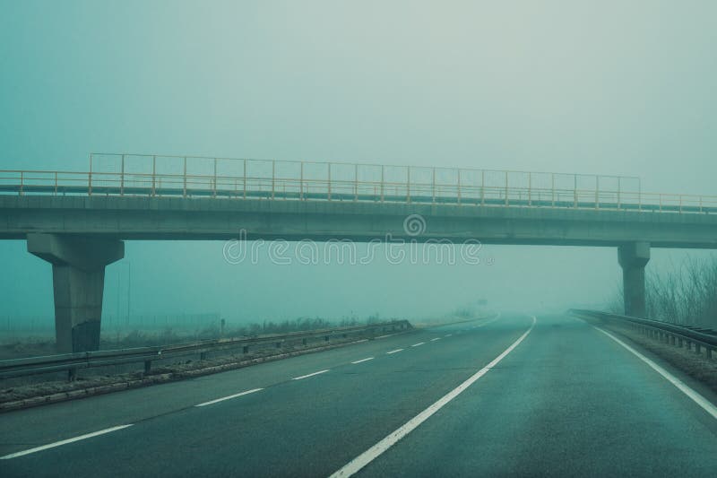 Leere Landstrasse im nebligen Wintermorgen lizenzfreie stockfotografie