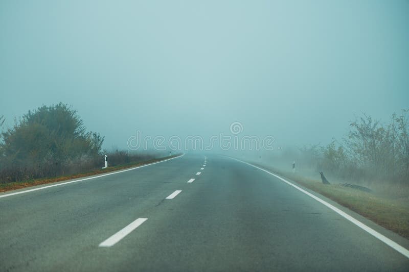 Leere Nebelstraße im kalten Herbst bei schlechten Witterungsbedingungen für das Fahren lizenzfreie stockfotos