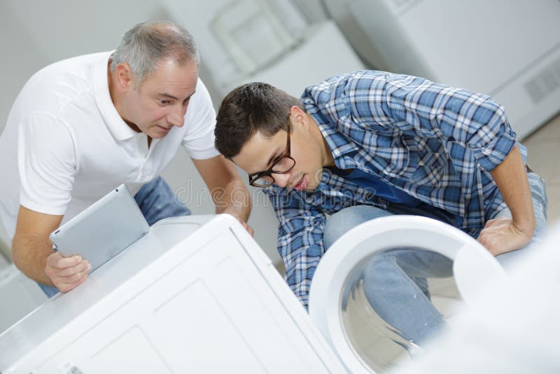 Leerlingshersteller met instructeur die wasmachine herstellen royalty-vrije stock afbeeldingen Leerlingshersteller met instructeur die wasmachine herstellen royalty-vrije stock afbeeldingen