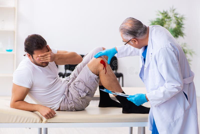 Leg Injured Man Visiting Old Doctor in First Aid Concept Stock Photo