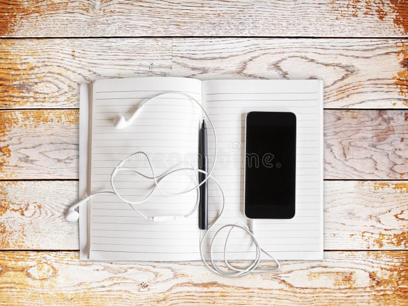 Blank cell phone with headphones and diary, close up. Blank cell phone with headphones and diary, close up