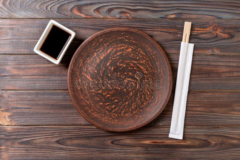 Lege donkere uitstekende ronde plaat met eetstokjes voor sushi op houten achtergrond Hoogste mening met exemplaarruimte royalty-vrije stock afbeeldingen Lege donkere uitstekende ronde plaat met eetstokjes voor sushi op houten achtergrond Hoogste mening met exemplaarruimte royalty-vrije stock afbeeldingen