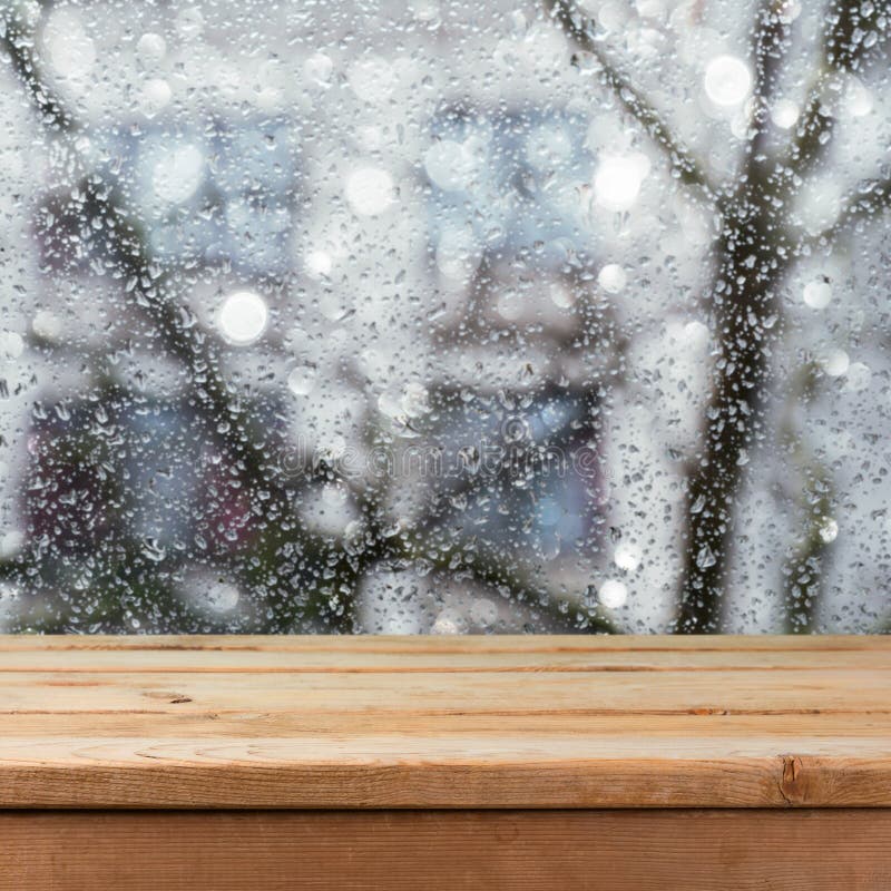 Lege houten deklijst over nat glasvenster Regenachtig weerconcept