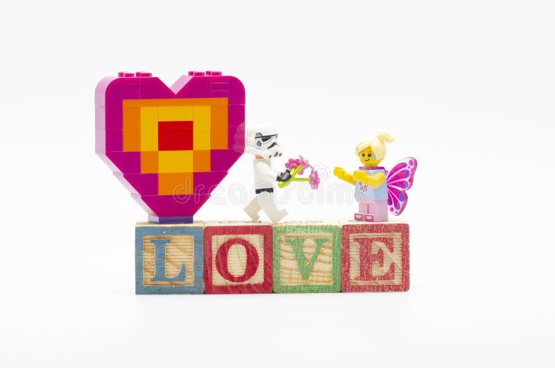 Lego storm trooper δίνει λουλούδι σε κορίτσι πεταλούδα με λέξη αγάπη χρησιμοποιώντας ξύλινο αλφάβητο. Lego ερωτικό σχήμα με λέξη love με αλφάβητο ξύλινο τούβλο απομονωμένο σε λευκό φόντο