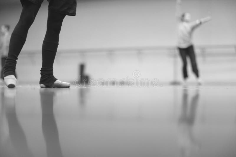 Legs of ballerina dancing in pointe in warm socks at rehearsal in the hall