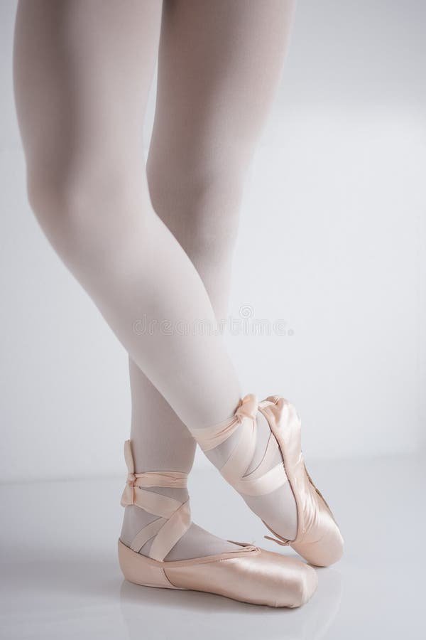 Legs and feet with pink satin pointe shoes by a classical dancer posing