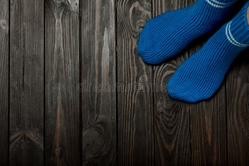 Legs knitted blue woolen socks on wooden dark background. stock photos Legs knitted blue woolen socks on wooden dark background. stock photos