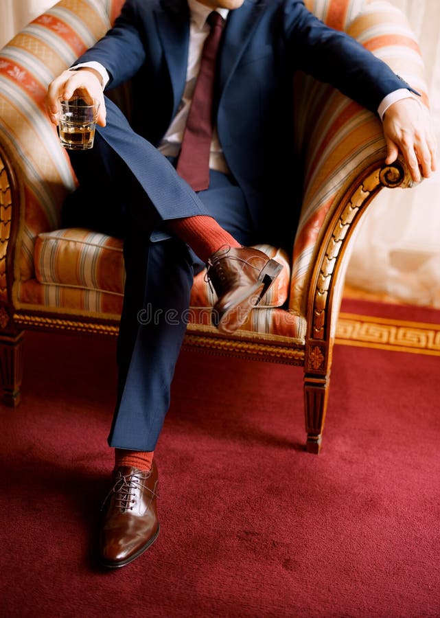 legs man blue pants red socks brown shoes sitting chair holding glass one hand legs man blue pants 234462933