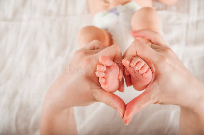 Legs of a newborn in hands closeup. Baby`s feet and copy space. Infant care and colic.