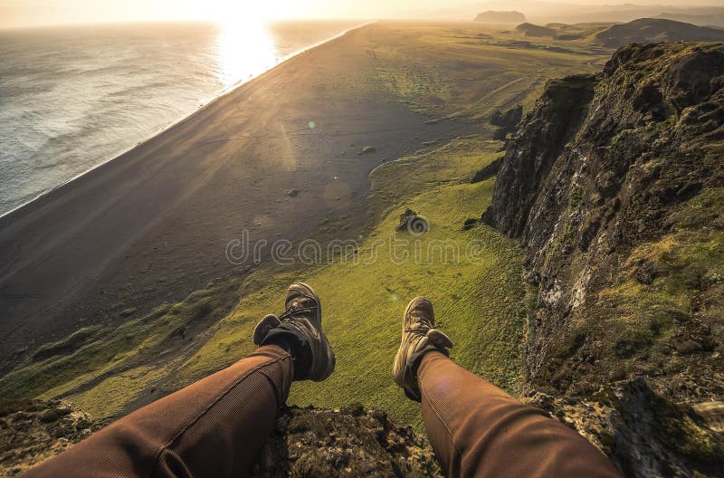 Legs of tourist in tracking shoes and view of Black sand beach in Iceland stock photography Legs of tourist in tracking shoes and view of Black sand beach in Iceland stock photography