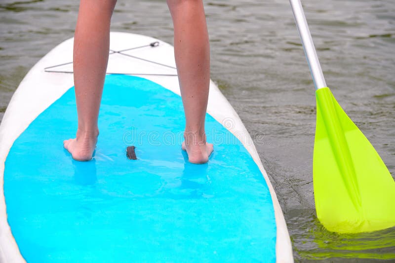 Legs of a young woman standing on a paddle board on the surface of the river stock images Legs of a young woman standing on a paddle board on the surface of the river stock images