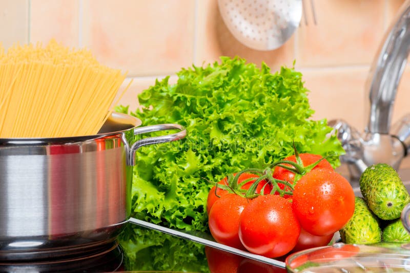 legumes frescos e um potenciômetro dos espaguetes na cozinha foto de stock legumes frescos e um potenciômetro dos espaguetes na cozinha foto de stock