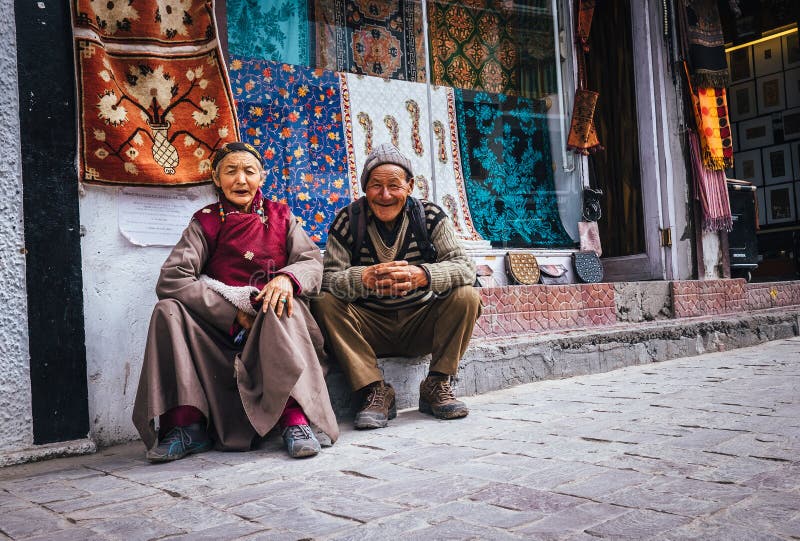 Leh , Ladakh region , India - August 20, 2016: Old Ladakhi people couple carpet sellers sitting on the street in Leh, India. Leh , Ladakh region , India - August 20, 2016: Old Ladakhi people couple carpet sellers sitting on the street in Leh, India