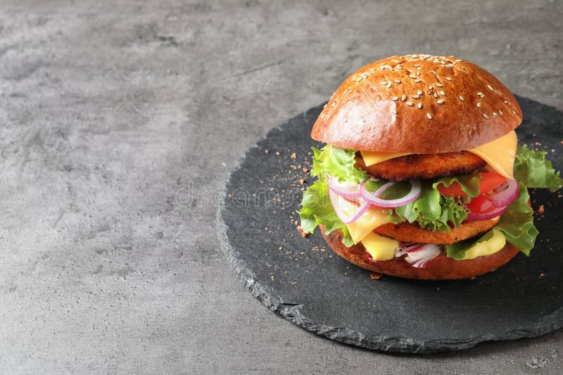 Leiplaat met dubbele vegetarische hamburger op grijze achtergrond stock fotografie Leiplaat met dubbele vegetarische hamburger op grijze achtergrond stock fotografie