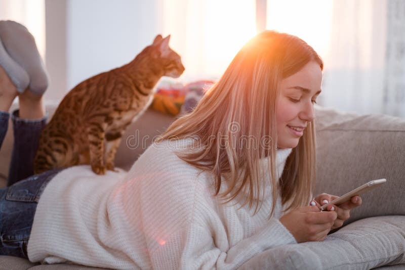 Leisure time. happy pastime with animal companion. girl laying on comfortable sofa with her pet at home browsing her phone. Leisure time. happy pastime with animal companion. girl laying on comfortable sofa with her pet at home browsing her phone