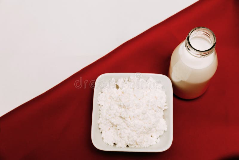 Leite em um requeijão da garrafa e em bagas da cereja em um fundo vermelho e branco fotos de stock Leite em um requeijão da garrafa e em bagas da cereja em um fundo vermelho e branco fotos de stock