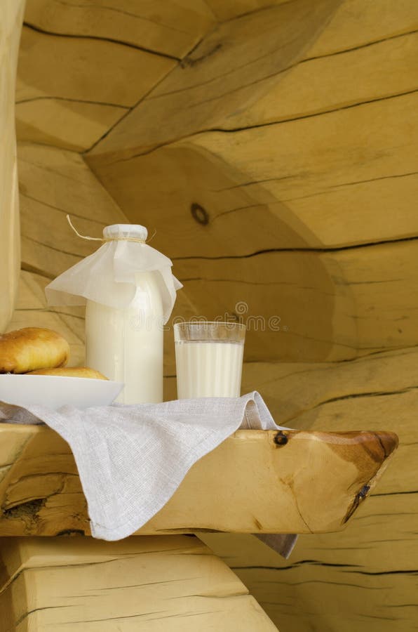 Leite fresco em uma garrafa de vidro e em um vidro, ao lado das tortas em uma tabela de madeira O conceito de produtos org?nicos imagem de stock Leite fresco em uma garrafa de vidro e em um vidro, ao lado das tortas em uma tabela de madeira O conceito de produtos org?nicos imagem de stock
