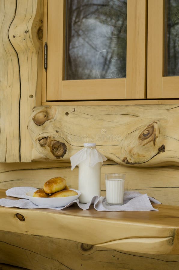 Leite fresco em uma garrafa de vidro e em um vidro, ao lado das tortas em uma tabela de madeira O conceito de produtos org?nicos imagens de stock Leite fresco em uma garrafa de vidro e em um vidro, ao lado das tortas em uma tabela de madeira O conceito de produtos org?nicos imagens de stock