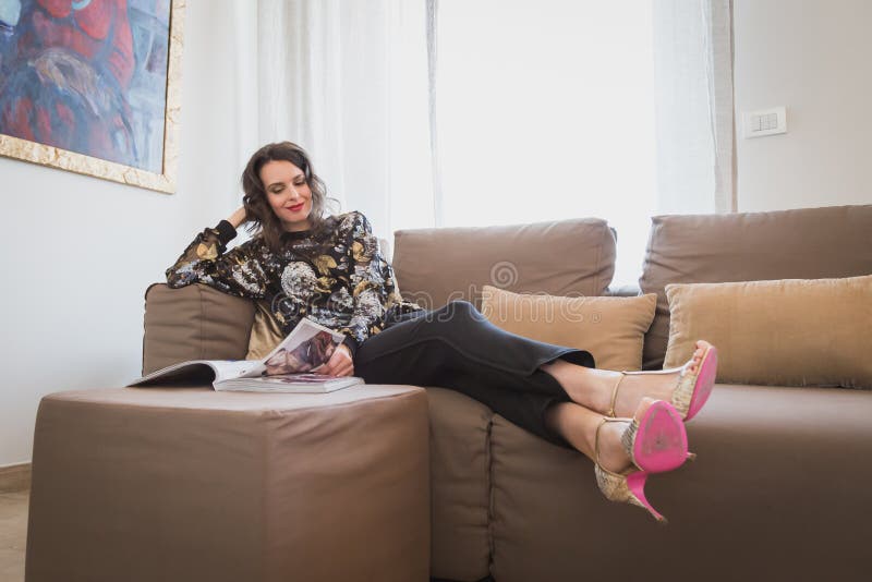 Uma jovem morena bonita a ler no sofá imagens de stock royalty free