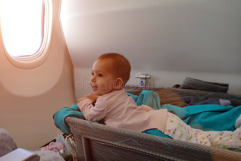 Lejías infantiles felices del bebé en cuna especial en aeroplano en su estómago Primer vuelo del bebé, la impresionan y las sonri imagenes de archivo Lejías infantiles felices del bebé en cuna especial en aeroplano en su estómago Primer vuelo del bebé, la impresionan y las sonri imagenes de archivo