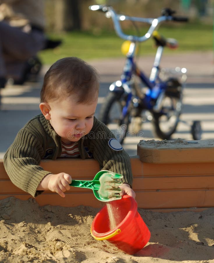 Young boy is playing outdoor in a sand pit. Young boy is playing outdoor in a sand pit.