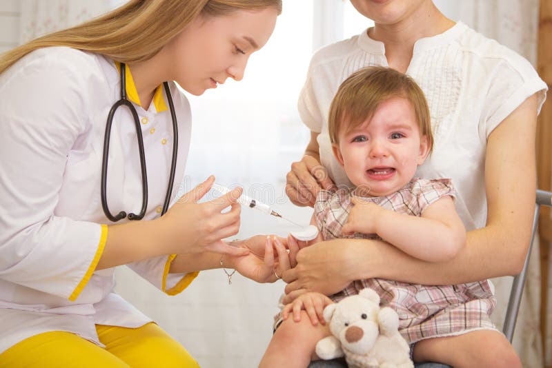 A doctor giving a crying child an injection at home. A doctor giving a crying child an injection at home.