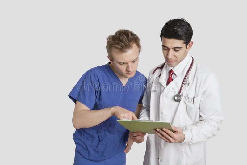 Lekarka i męska pielęgniarka dyskutuje raport medycznego nad szarym tłem