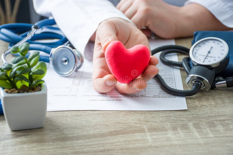 Lekarka wewnętrznej medycyny i kardiologa mienie w jego ręki i przedstawienia cierpliwa postać czerwonej kartki serce podczas med
