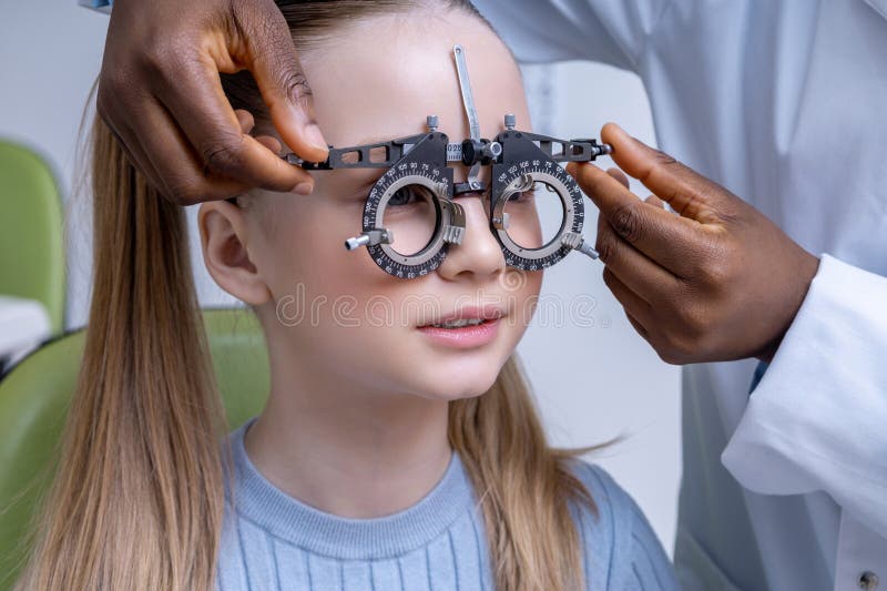Lekarz dostosowujący narzędzie optometryczne podczas badania widzenia dziewczyny obraz royalty free