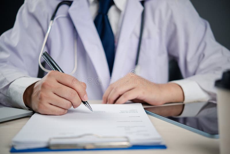 Lekarz piszący na formularzu medycznym lub na tablicy receptowej symbolizujący diagnozę pacjenta i fotografia royalty free