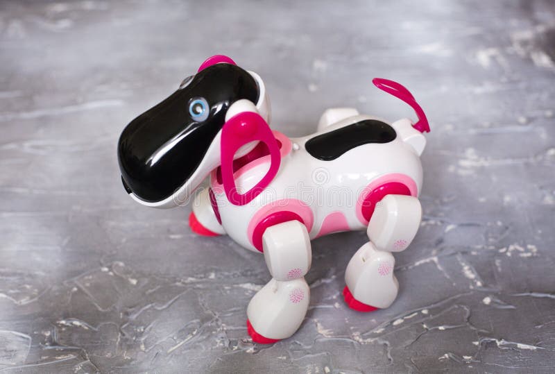 Leksakrobotvit och rosa färger, på en konkret bakgrund Hunden är en robot royaltyfri fotografi