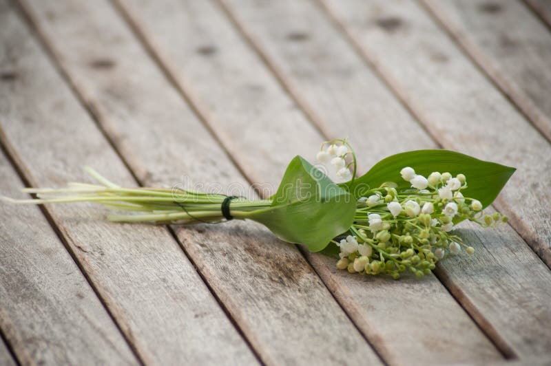 Closeup of lily of the valley bouquet on wooden table background. Closeup of lily of the valley bouquet on wooden table background