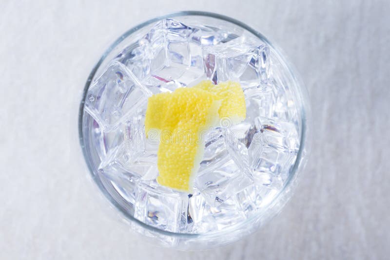 Top view of a gin tonic balloon glass with lemon peels on it on a flavoring process - gin tonic session - focus on peel. Top view of a gin tonic balloon glass with lemon peels on it on a flavoring process - gin tonic session - focus on peel